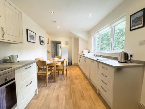 a kitchen with white cabinets and a table and a dining room at RIDGEMOUNT APT - Great base for walking and cycling in Keswick, Lake District National Park in Keswick