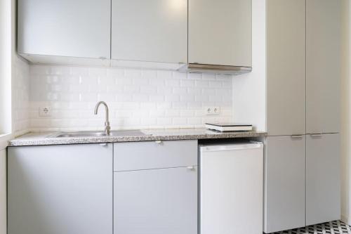 a white kitchen with white cabinets and a sink at Oporto Seaside Village - Casa Praia in Matosinhos