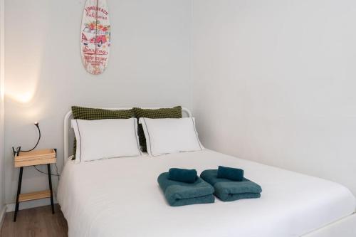 a white bed with two blue pillows on it at Oporto Seaside Village - Casa Praia in Matosinhos