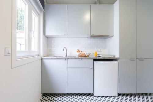 a white kitchen with white cabinets and a sink at Oporto Seaside Village - Casa Praia in Matosinhos
