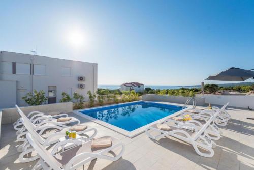 a villa with a swimming pool and lounge chairs at Villa Domenica - Luxury Apartment with Pool, Hot Tub & Sea View in Novalja