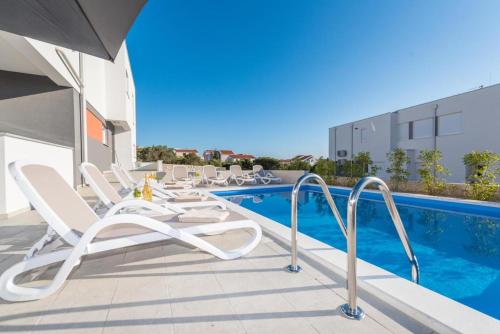 a patio with chairs and a swimming pool at Villa Domenica - Luxury Apartment with Pool, Hot Tub & Sea View in Novalja