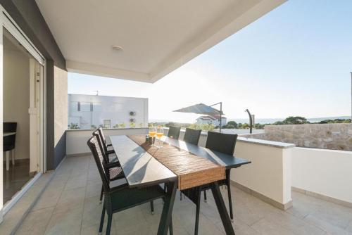 a dining room with a table and chairs on a balcony at Villa Domenica - Luxury Apartment with Pool, Hot Tub & Sea View in Novalja