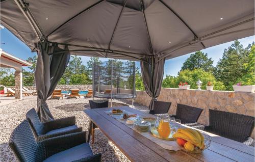 ein Holztisch mit Obst darauf unter einem großen Sonnenschirm in der Unterkunft Four-Bedroom Holiday Home In Imotski in Imotski