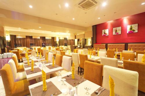 a restaurant with white tables and yellow chairs at Nagoya Mansion Hotel and Residence in Nagoya