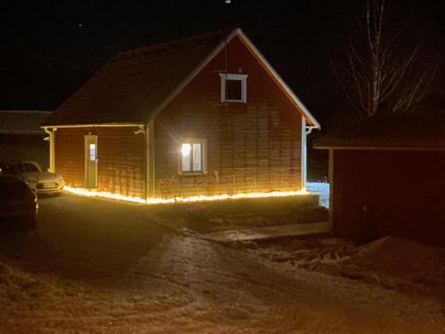 a house with lights on the side of it at night at Sjöutsikt, Röd trästuga med traditionellt yttre Skandinavisk, modernt inre och alla bekvämligheter, Sol hela dagen på stora altanen, Tryggt, Vinterbonat, Fiske, Båt in Skinnskatteberg