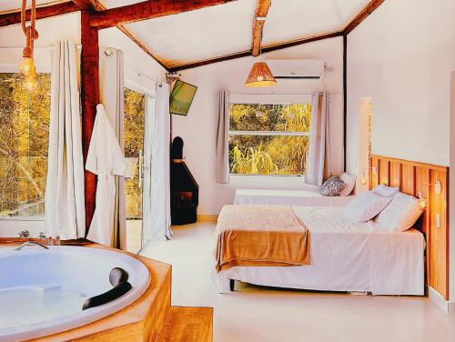 a bedroom with a bed and a bath tub at Vivenda Apua Chalés in Piracaia