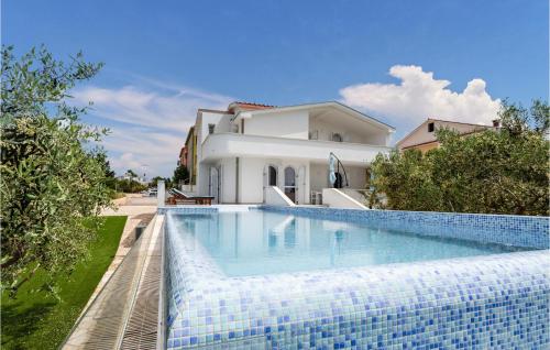 a swimming pool in front of a white house at Gorgeous Home In Povljana in Povljana
