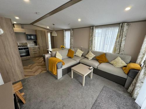 a living room with a gray couch and yellow pillows at Golden Palm Resort - The Stonewood - Coastal Caravan Breaks in Chapel Saint Leonards