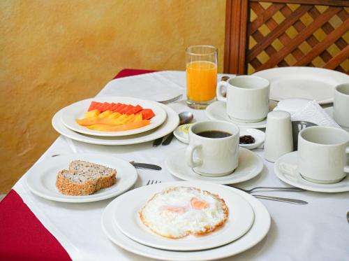 a table with plates of food and cups of coffee at Hotel Sol de la Villa in Villa de Leyva
