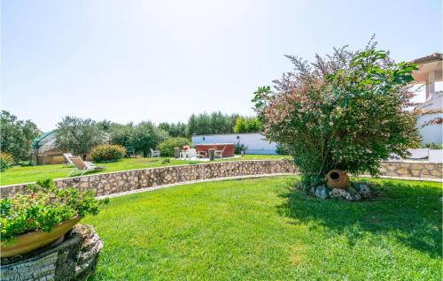 a garden with a stone wall and a tree at 2 Bedroom Cozy Home In Sabaudia in Sabaudia