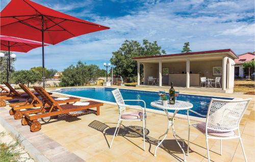 - une piscine avec des chaises et une table avec un parasol rouge dans l'établissement Apartment Peroj Ii, à Vodnjan