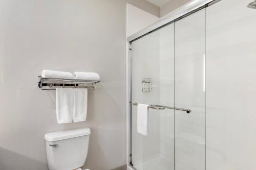 a bathroom with a shower and a toilet with towels at Holiday Inn Express Hotel and Suites Alice by IHG in Alice