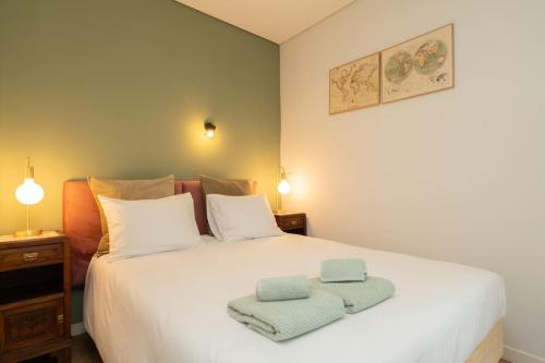 a bedroom with a white bed with two towels on it at Oporto Seside Village - Casa Mar in Matosinhos