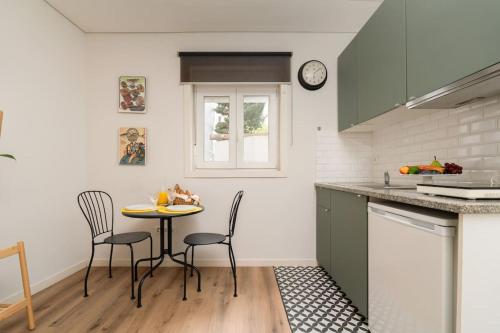 a kitchen with a table and chairs and a clock at Oporto Seside Village - Casa Mar in Matosinhos