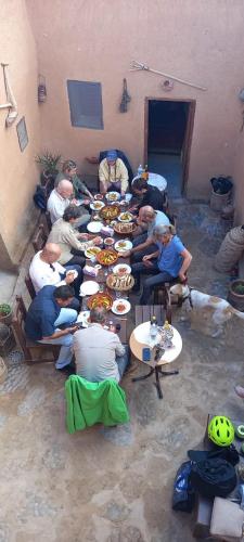 a group of people sitting at tables eating food at Maison d'hôte sirwaji in Assa