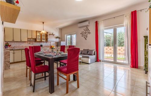 a kitchen and dining room with a table and red chairs at 3 Bedroom Amazing Home In Liznjan in Šišan