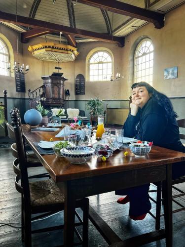 a woman sitting at a table talking on a cell phone at Pieter Stuyvesantkerk Peperga-Friesland in Peperga