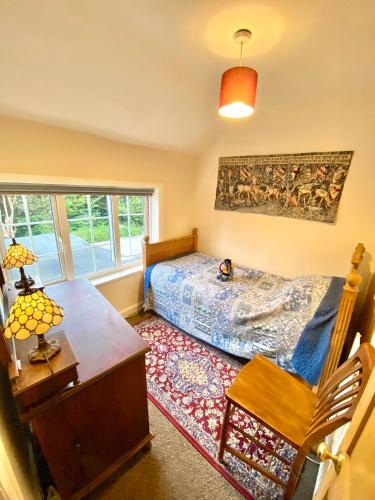 a bedroom with a bed and a table and a window at Bumblebee Cottage in Knowle