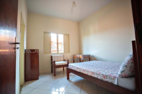 a bedroom with a bed and a chair and a window at Casa em Baependi-Até 7 pessoas in Baependi