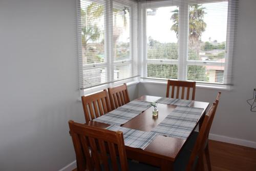 a dining room table with chairs and two windows at Woodford Living in Auckland