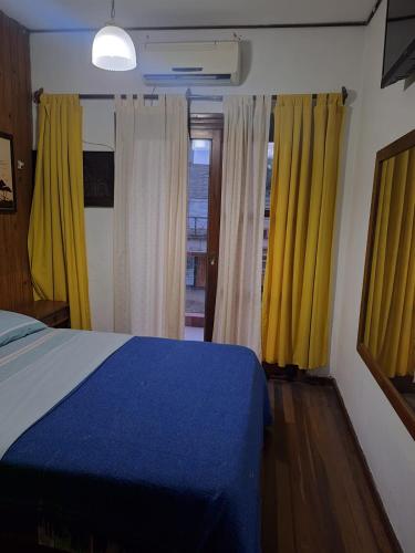 a bedroom with yellow curtains and a blue bed at Morada urbana pleno centro in Posadas