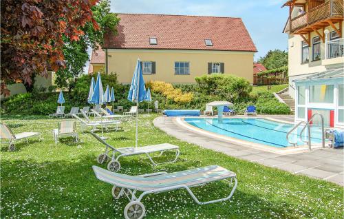 a pool with chairs and umbrellas next to a house at Biodorf Bad Waltersdorf in Bad Waltersdorf