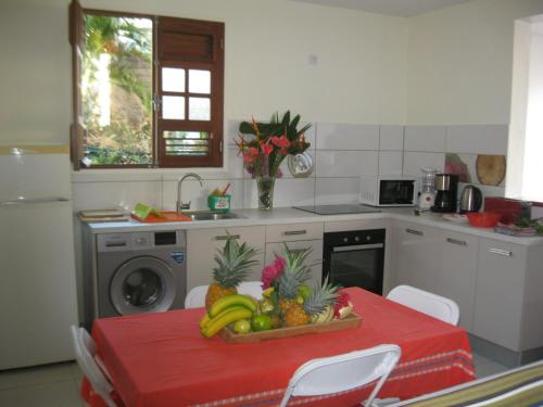 a kitchen with a table with a bowl of fruit on it at LAPALOMADESANSEs2 in Les Anses-dʼArlets