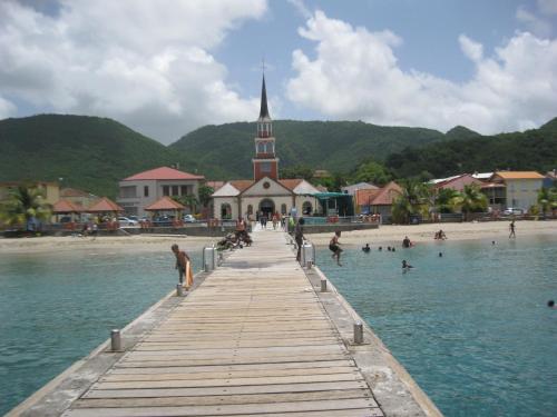 a pier leading to a beach with a church at LAPALOMADESANSEs2 in Les Anses-dʼArlets