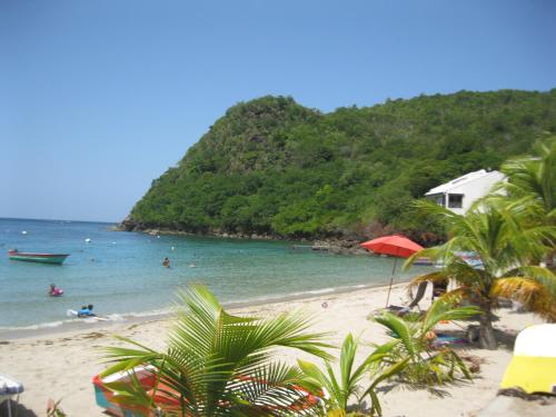 a beach with people in the water and a mountain at LAPALOMADESANSEs2 in Les Anses-dʼArlets