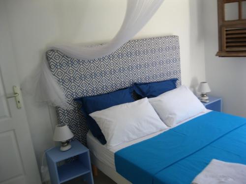 a blue and white bed in a bedroom with two tables at LAPALOMADESANSEs2 in Les Anses-dʼArlets