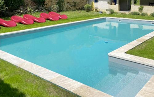 a swimming pool with red chairs in the grass at Beautiful Home In Pech-Luna With Wi-Fi in Pech-Luna