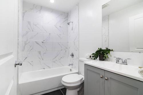 a white bathroom with a tub and a toilet and a sink at 2BR Plus Bonus Room and Pool Access Near Universal Studios in Los Angeles