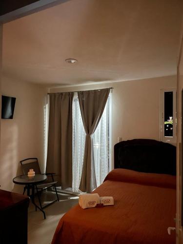 a bedroom with a bed and a window and a table at Galex Hotel Posada in Huajuapan de León