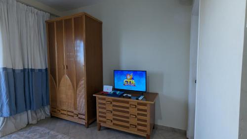a living room with a tv and a wooden cabinet at Golf Heights Resort - Sea and Mountain View - Free WIFI - Sharm El Sheikh in Sharm El Sheikh