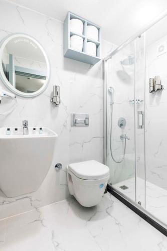 a white bathroom with a toilet and a shower at Santa Rio Gold Taxim Hotel in Istanbul
