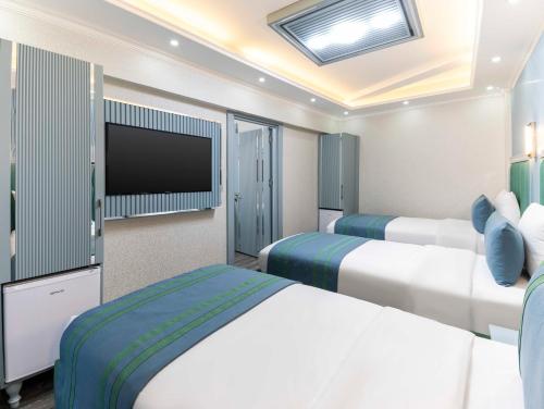 a hotel room with two beds and a flat screen tv at Santa Rio Gold Taxim Hotel in Istanbul