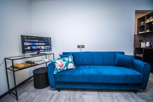 a blue couch in a living room with a tv at Szarvas City Apartman in Szarvas