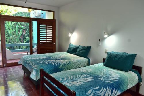 two beds in a room with a window at Hotel Planeta Sano in Manuel Antonio