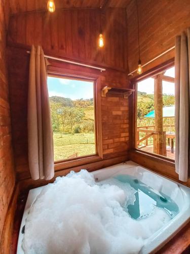 a bath tub filled with snow in a room with a window at Chalés Refúgio no Campo in Santo Antônio do Pinhal