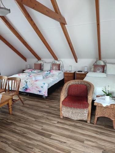 a attic room with two beds and a chair at Whitianga Luxurious studio room in Whitianga