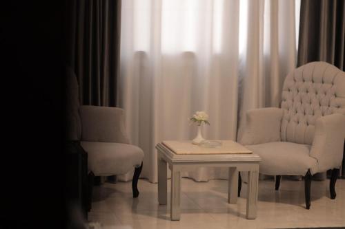 a room with two chairs and a table with a vase of flowers at Aura Inn Hotel Cairo in Cairo