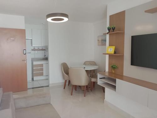 una cucina con tavolo e televisore in una stanza di La Palma 204 - Pé na Areia - Praia dos Milionários - Condomínio VOG Atlântico a Ilhéus