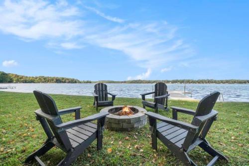 three chairs sitting around a fire pit by the water at Birch Tree Landing on Hamlin Lake in Ludington