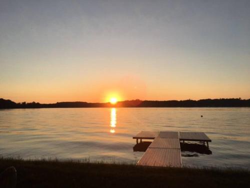 a dock on a lake with the sunset in the background at Birch Tree Landing on Hamlin Lake in Ludington