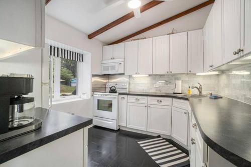 a kitchen with white cabinets and a black counter top at Birch Tree Landing on Hamlin Lake in Ludington