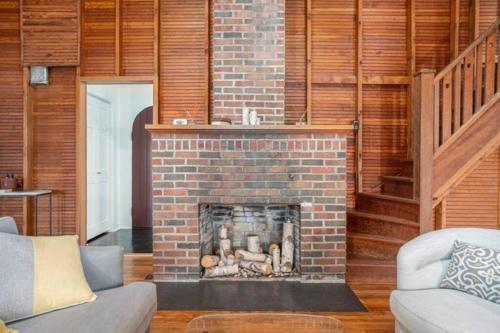 a brick fireplace in a living room with a staircase at Birch Tree Landing on Hamlin Lake in Ludington