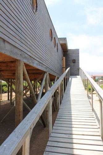a wooden boardwalk leading to a building at Exclusiva casa con vista panorámica al mar in Guanaqueros