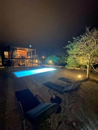 a group of blue lounge chairs in a pool at night at Exclusiva casa con vista panorámica al mar in Guanaqueros