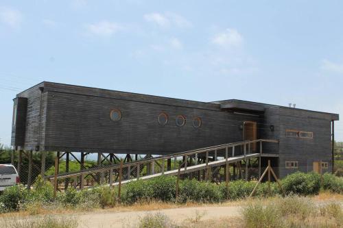 a black house with a wooden roof on a field at Exclusiva casa con vista panorámica al mar in Guanaqueros